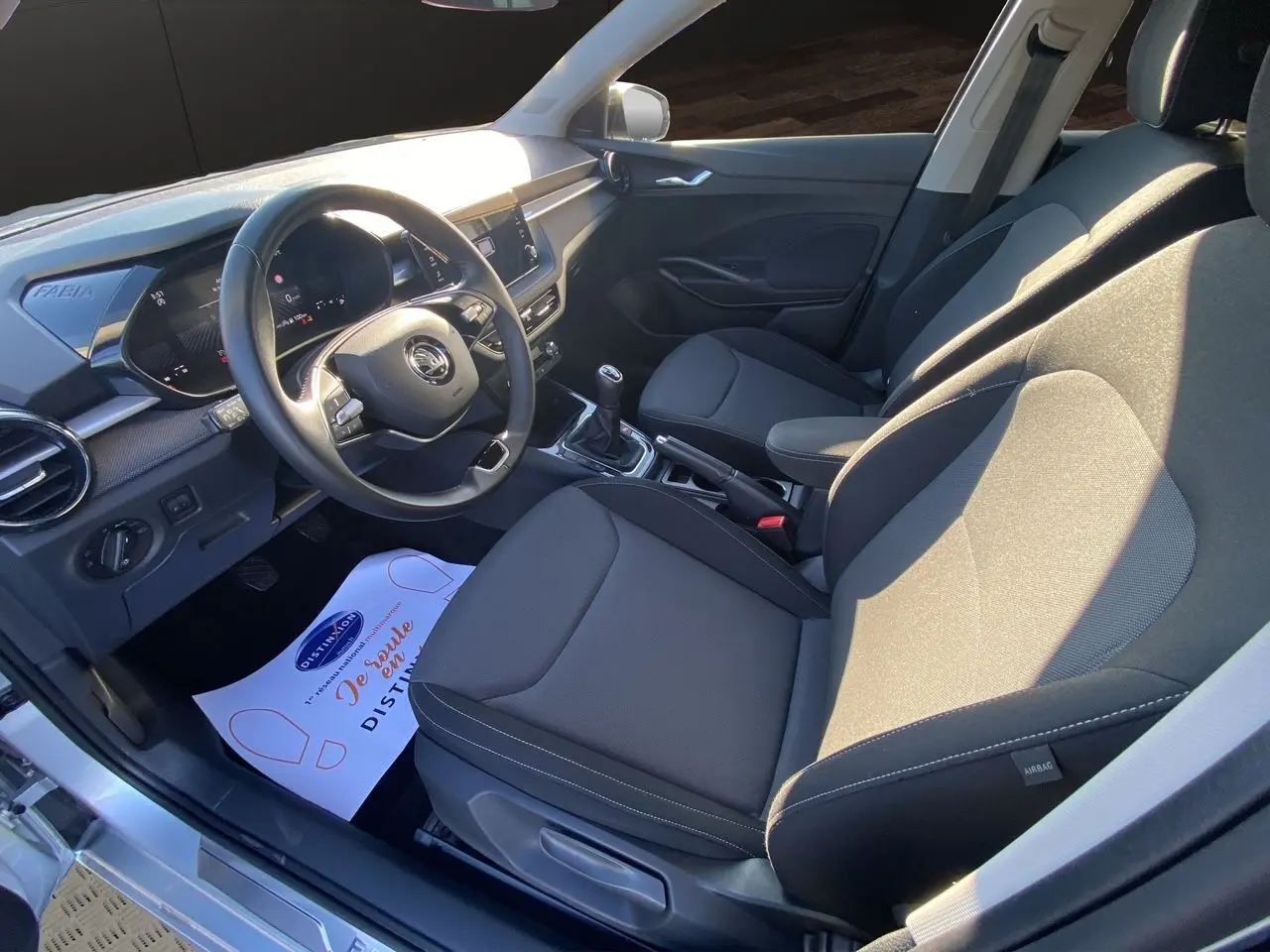 Intérieur avant droit de la Skoda Fabia 2024 avec sellerie tissu noire et console centrale avec boîte manuelle.