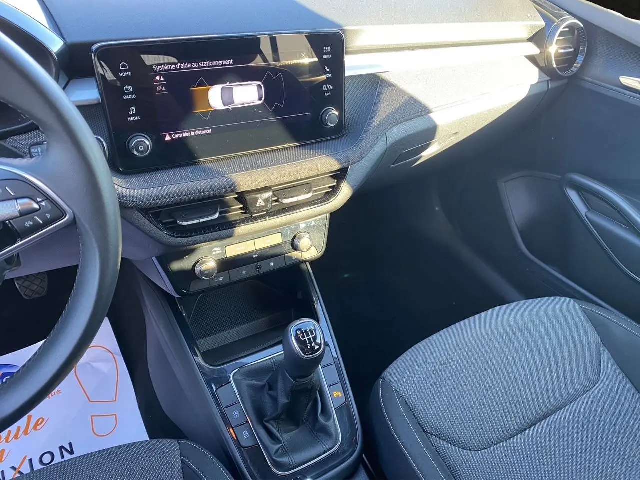 Intérieur avant droit d'une Skoda Fabia 2024 avec tableau de bord noir, écran tactile et levier de vitesse manuel.