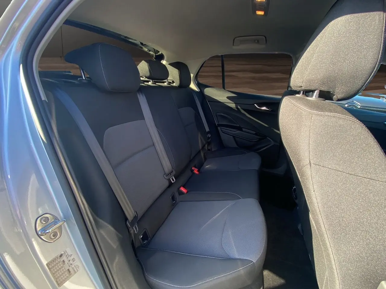 Vue intérieure côté gauche sur la banquette arrière tissu gris foncé avec appuie-têtes et ceintures de sécurité de la Skoda Fabia 2024.