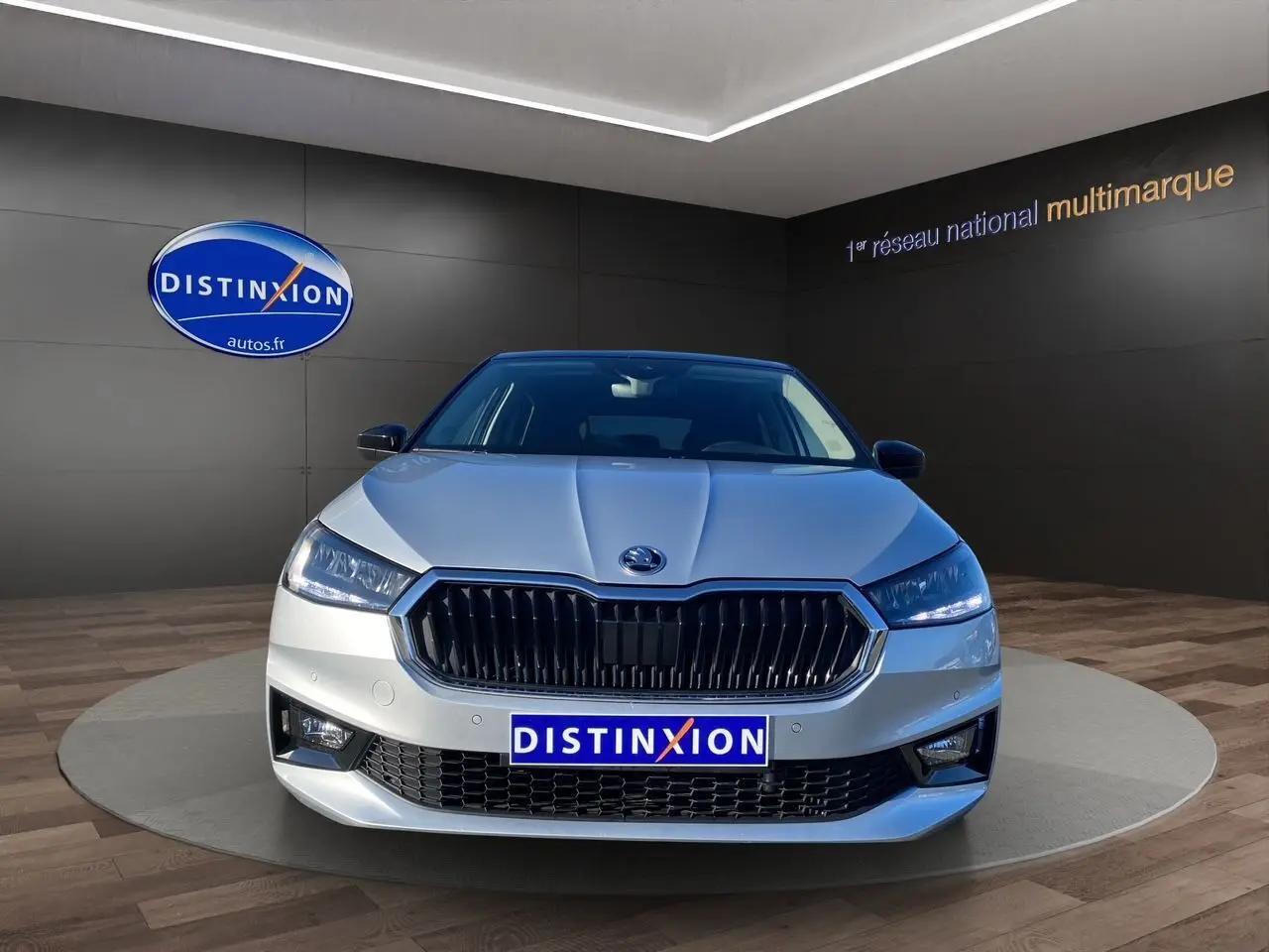 Vue frontale d'une Skoda Fabia gris clair avec calandre noire et phares LED dans un showroom.