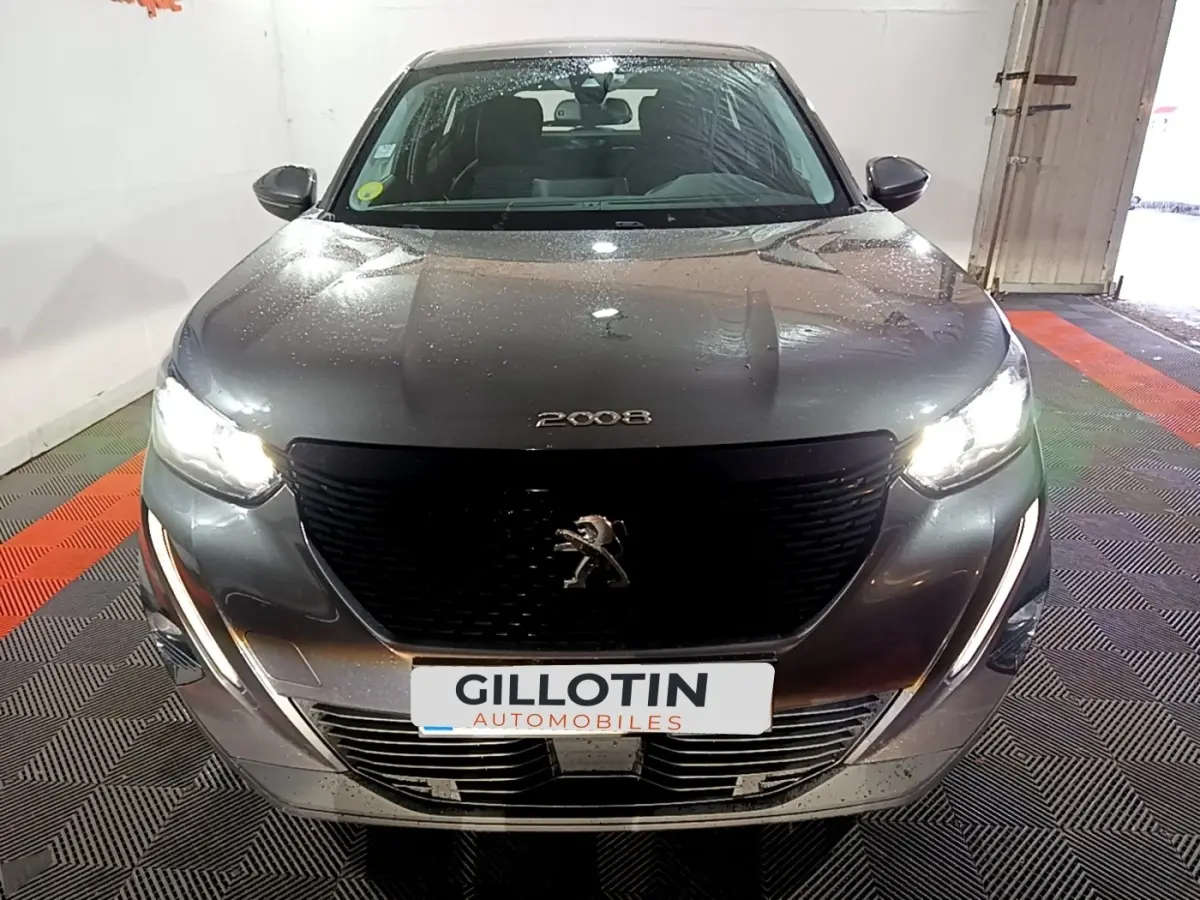 Vue avant d'un Peugeot 2008 gris clair avec phares allumés et calandre noire distinctive.