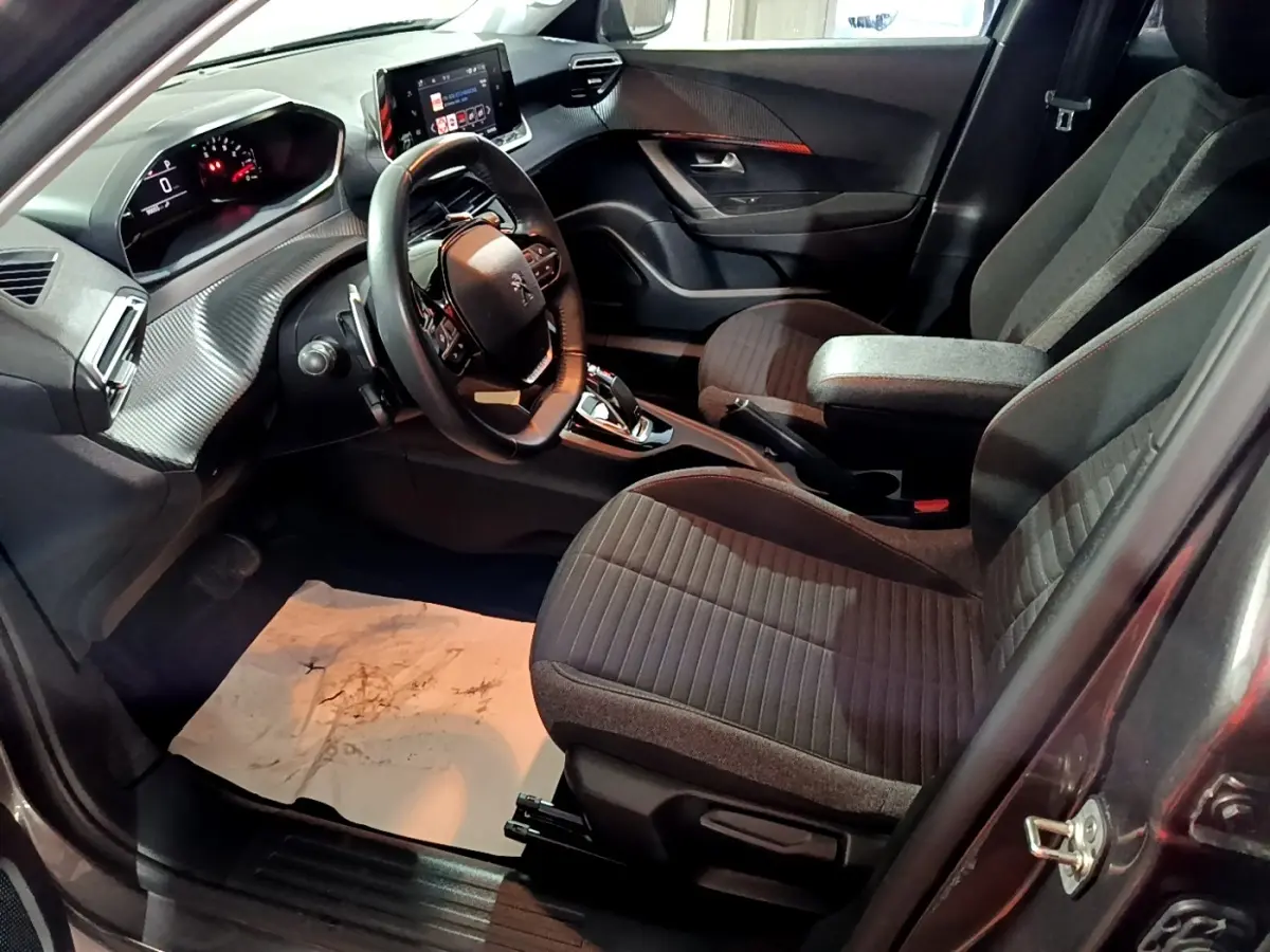 Vue intérieure côté conducteur du Peugeot 2008 gris clair 2021, volant cuir multifonctions et écran tactile central.