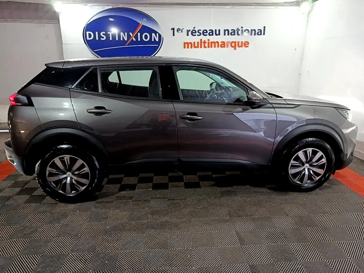 Peugeot 2008 gris clair vue de profil côté gauche dans un showroom avec logo Distinxion en arrière-plan.