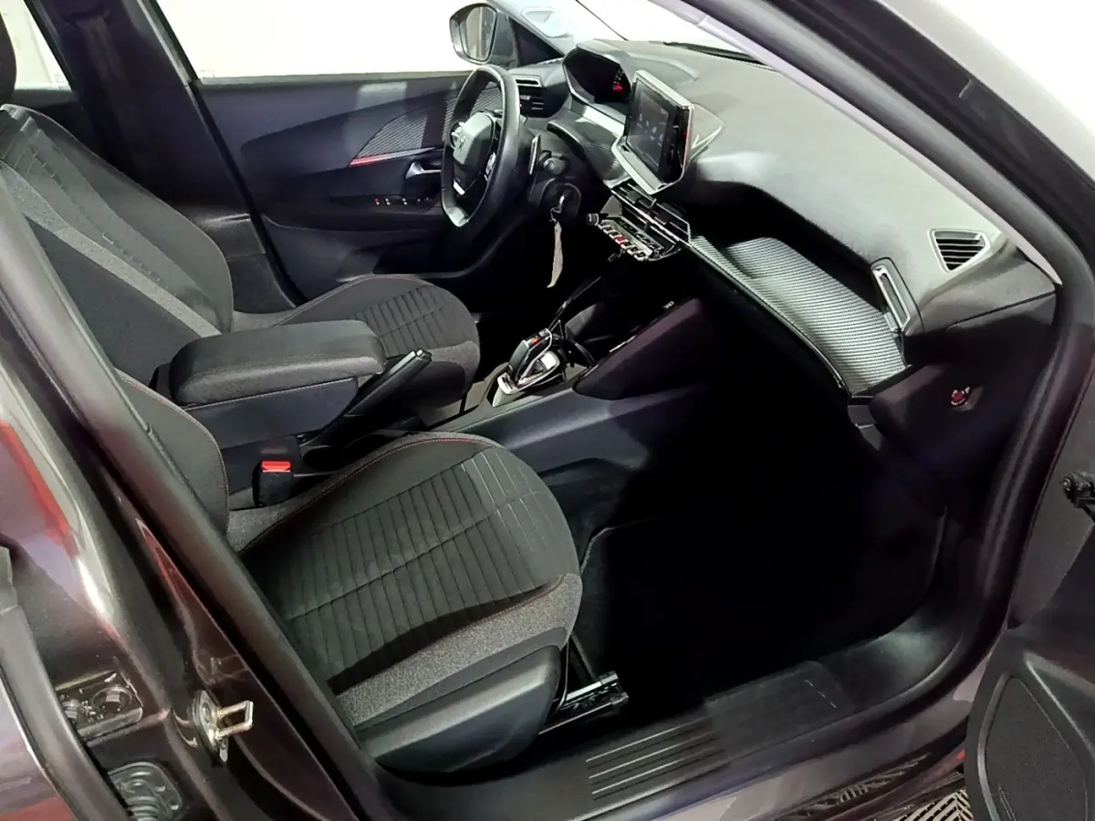 Vue intérieure côté conducteur de la Peugeot 2008 gris clair, avec volant cuir multifonctions et écran tactile central.