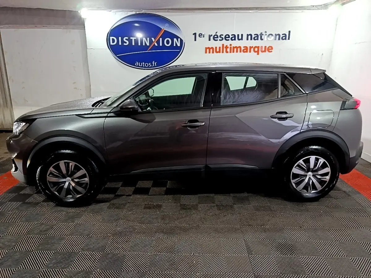 Profil droit du Peugeot 2008 gris clair 2021 garé en intérieur avec jantes alliage et vitres teintées.
