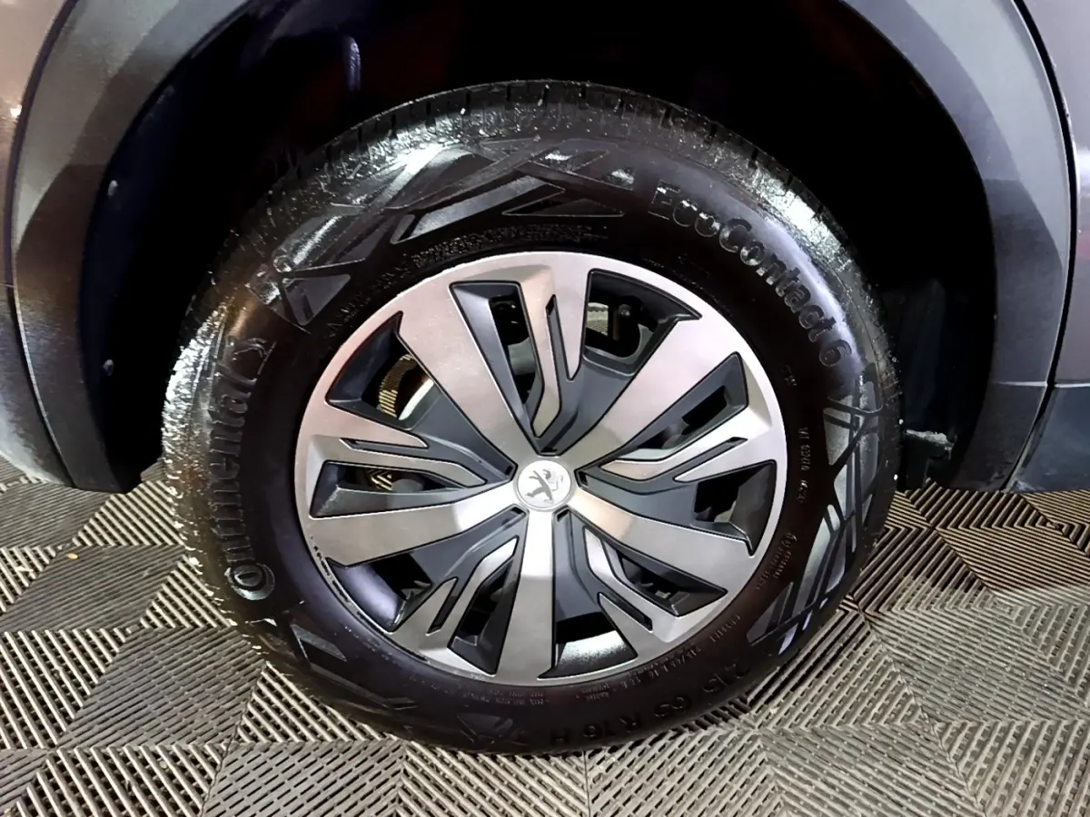 Gros plan sur la roue avant droite d’un Peugeot 2008 gris clair, avec jante alliage et pneu Continental.