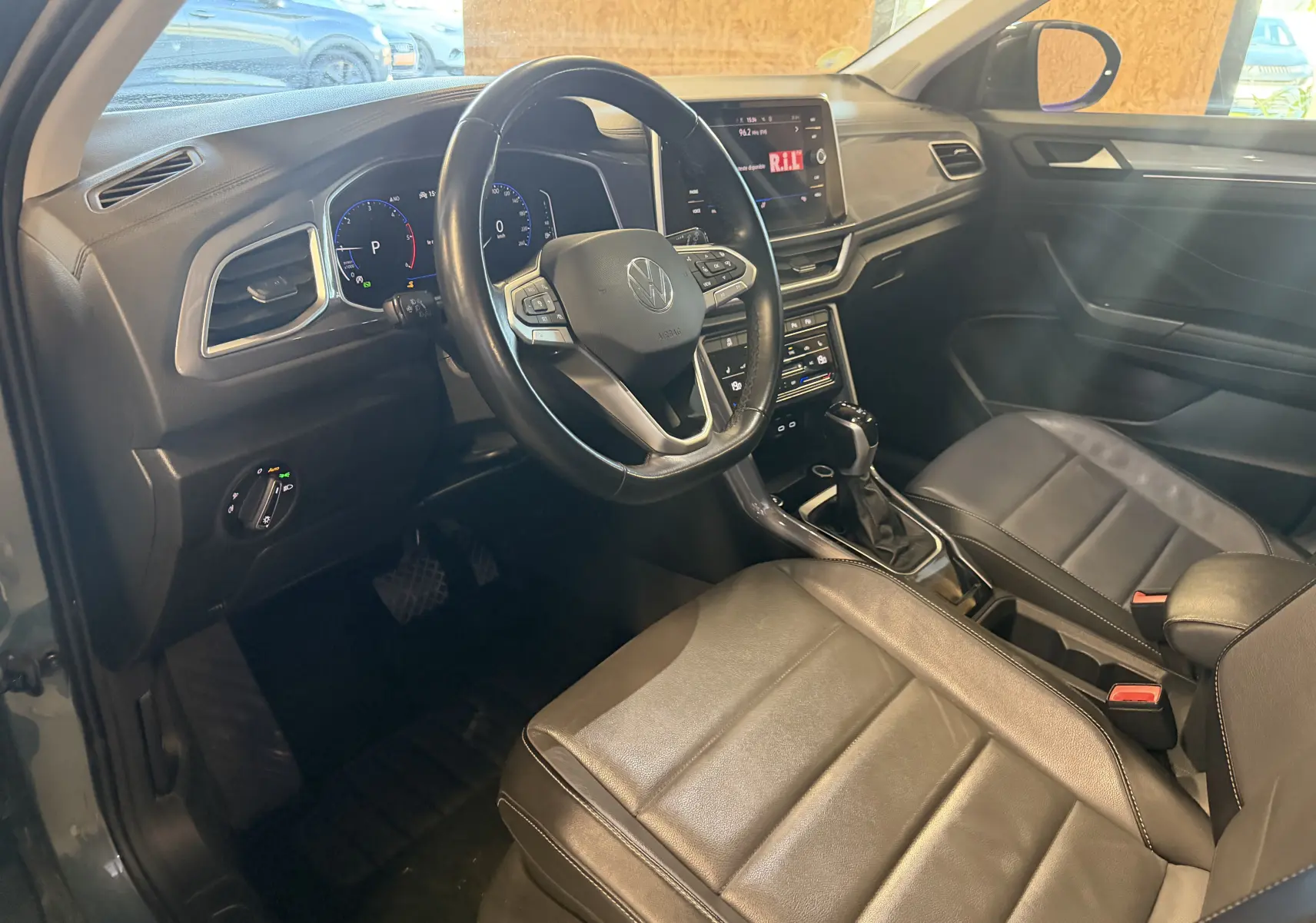 Vue intérieure côté conducteur du Volkswagen T-Roc bleu 2022, avec tableau de bord numérique et sellerie cuir noire.