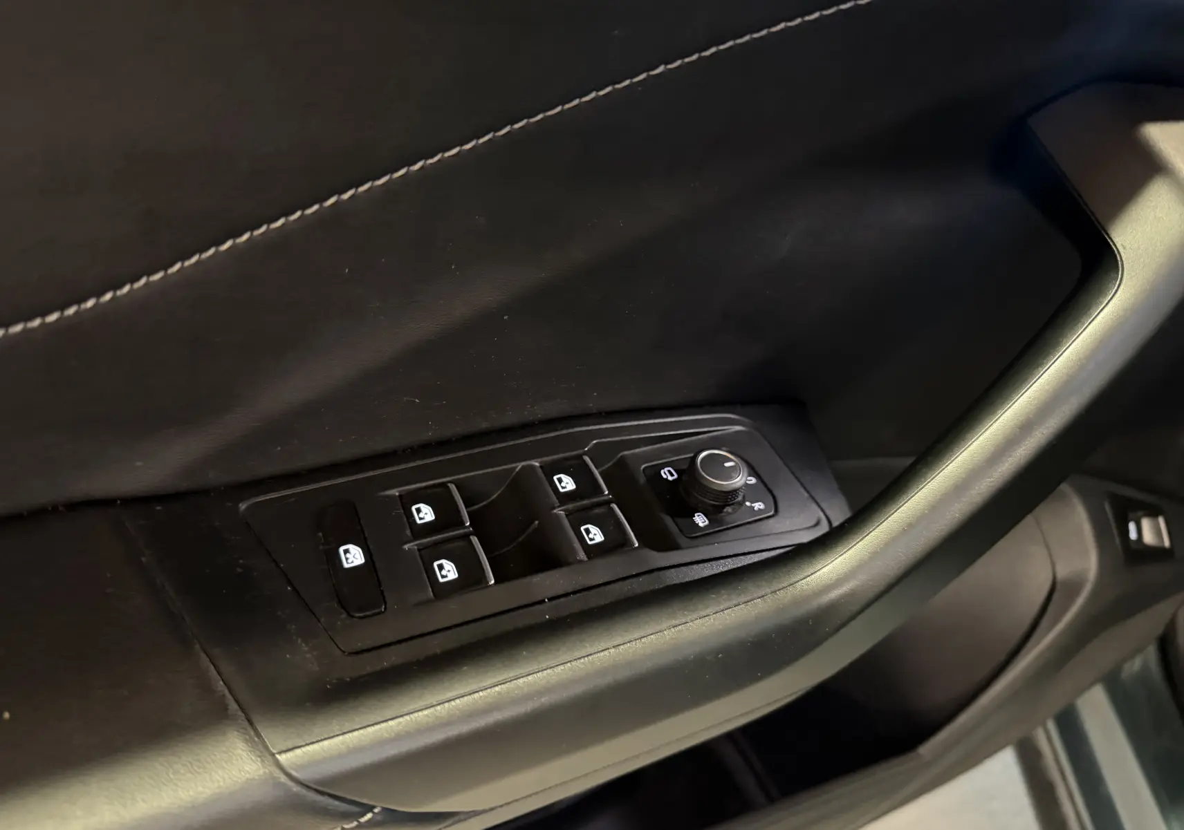 Gros plan sur les commandes de lève-vitres et rétroviseurs côté conducteur d’un Volkswagen T-Roc bleu 2022.