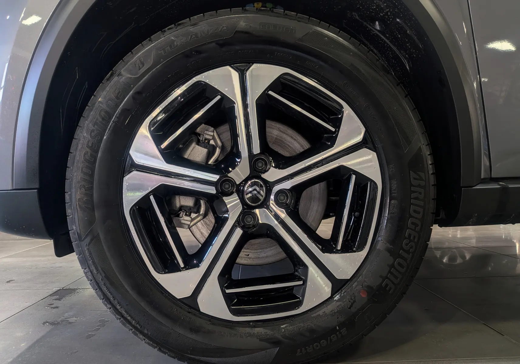 Gros plan sur la roue avant droite du Citroën C3 Aircross gris Mercury, jante alliage bicolore noire et argentée.