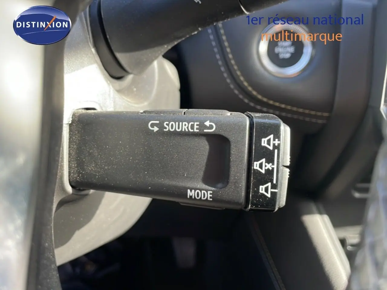 Gros plan sur la commande au volant avec boutons source et mode, intérieur noir du Renault Symbioz gris cassiopée métal.