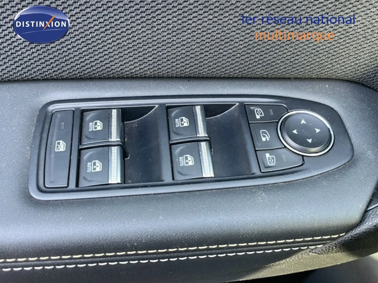 Panneau de commandes des vitres électriques et réglages des rétroviseurs côté conducteur, finition noire avec surpiqûres blanches.