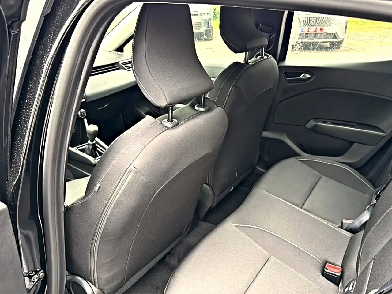 Vue intérieure côté gauche de la banquette arrière et des sièges avant noirs de la Renault Clio V 1.0 TCe 90 Evolution.