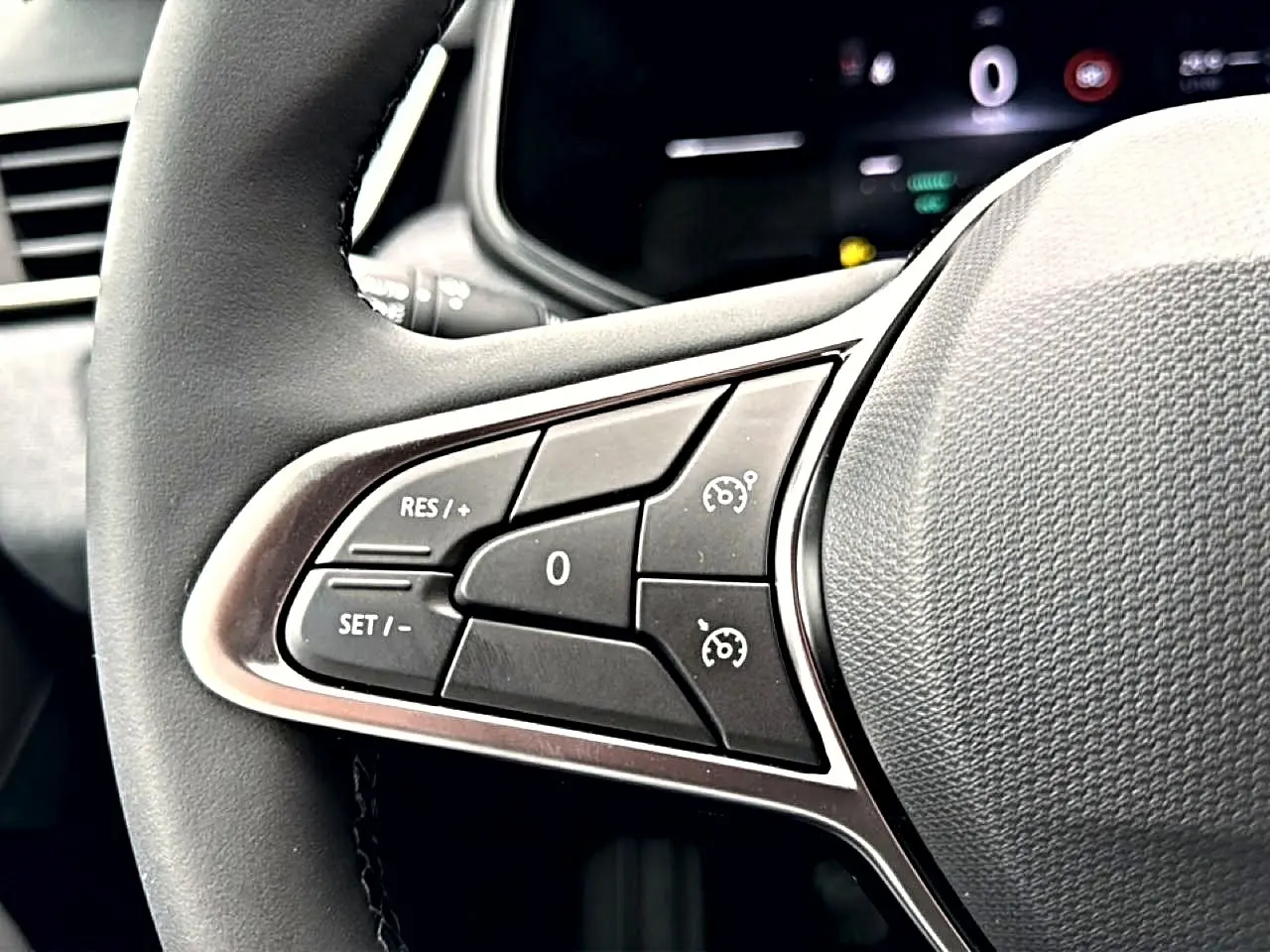 Gros plan sur les commandes du régulateur de vitesse au volant noir de la Renault Clio V 2026.