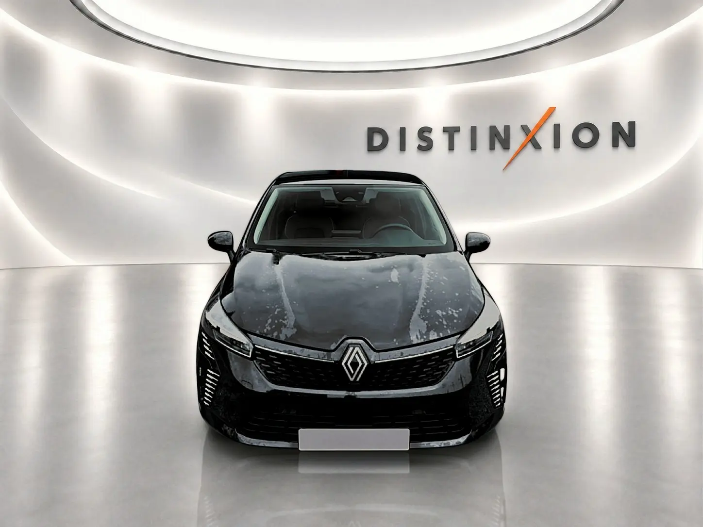 Renault Clio V noire vue de face, avec calandre distinctive et éclairage LED dans un showroom lumineux.