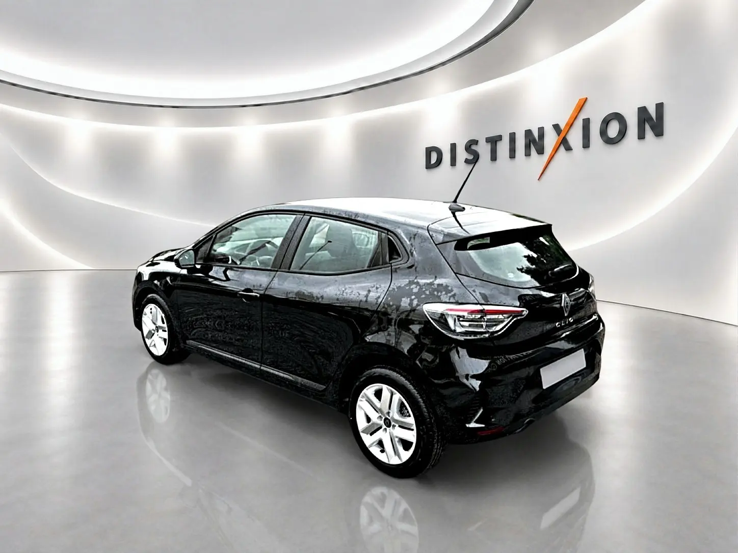 Renault Clio V noire vue 3/4 arrière droit dans un showroom lumineux avec logo Distinxion en arrière-plan.