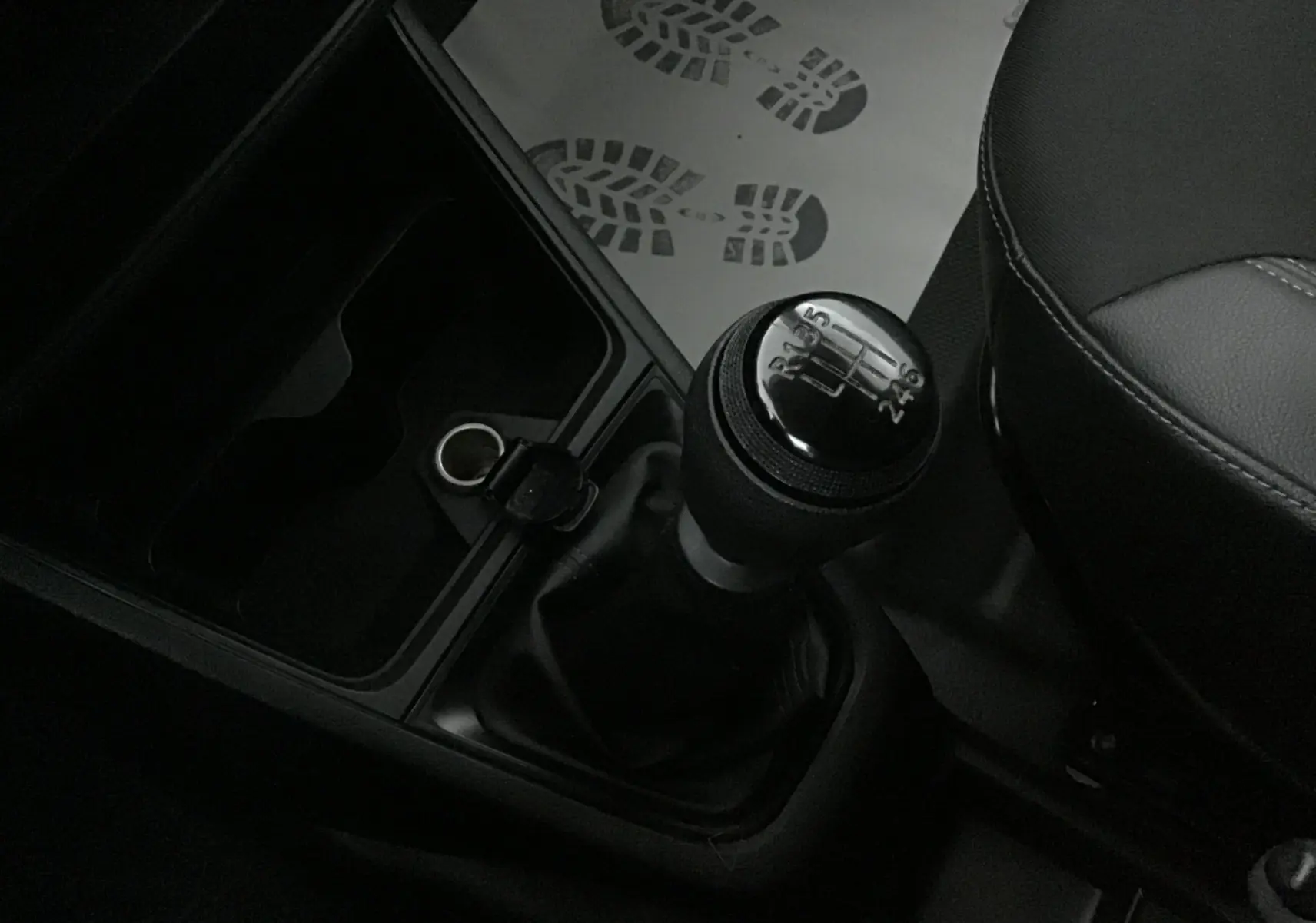 Le levier de vitesses manuel en gros plan dans l'habitacle sombre d'un Renault Express Van blanc.