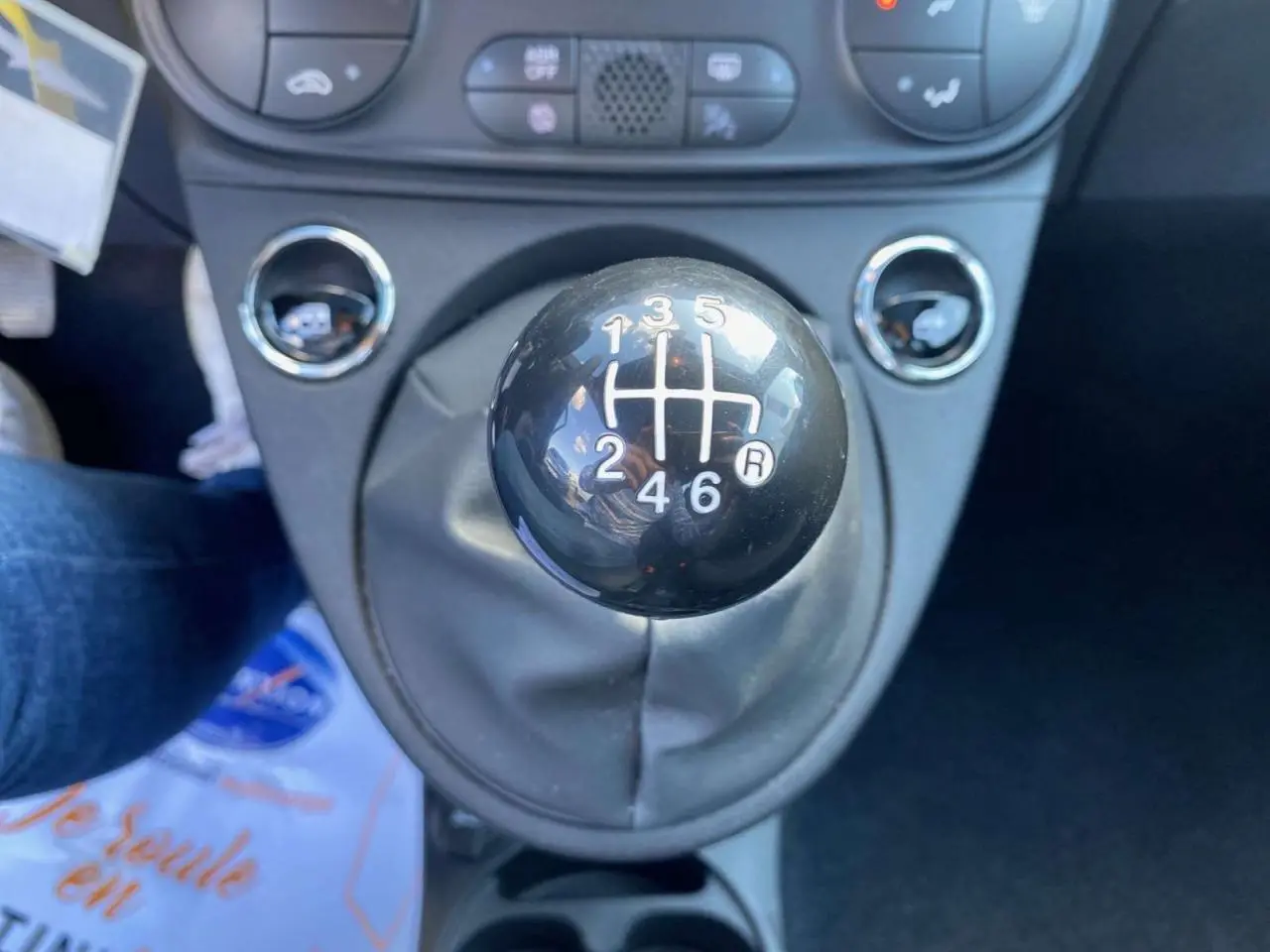 Gros plan sur le levier de vitesses manuel noir de la FIAT 500 2024, mettant en valeur la grille des six rapports.