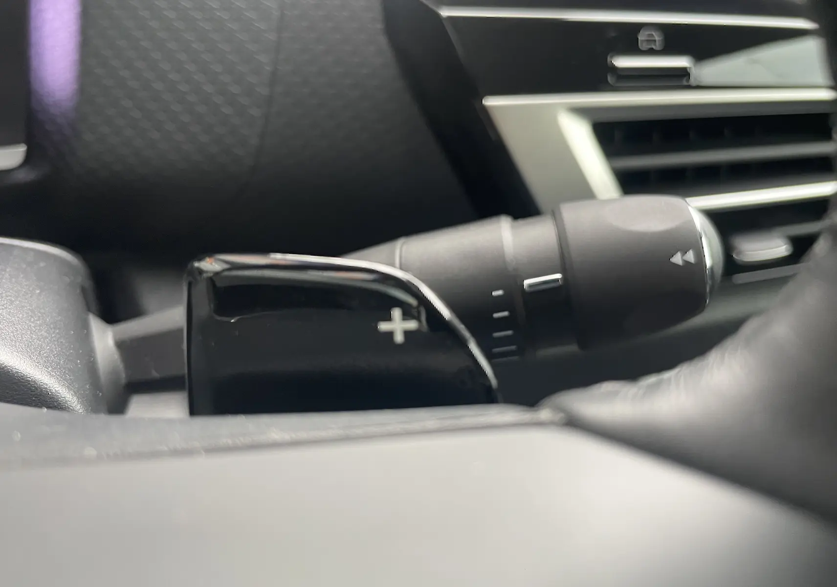 Gros plan sur la palette de changement de vitesse droite noire brillante dans l’habitacle gris foncé d’une Citroën C4 blanche 2022.