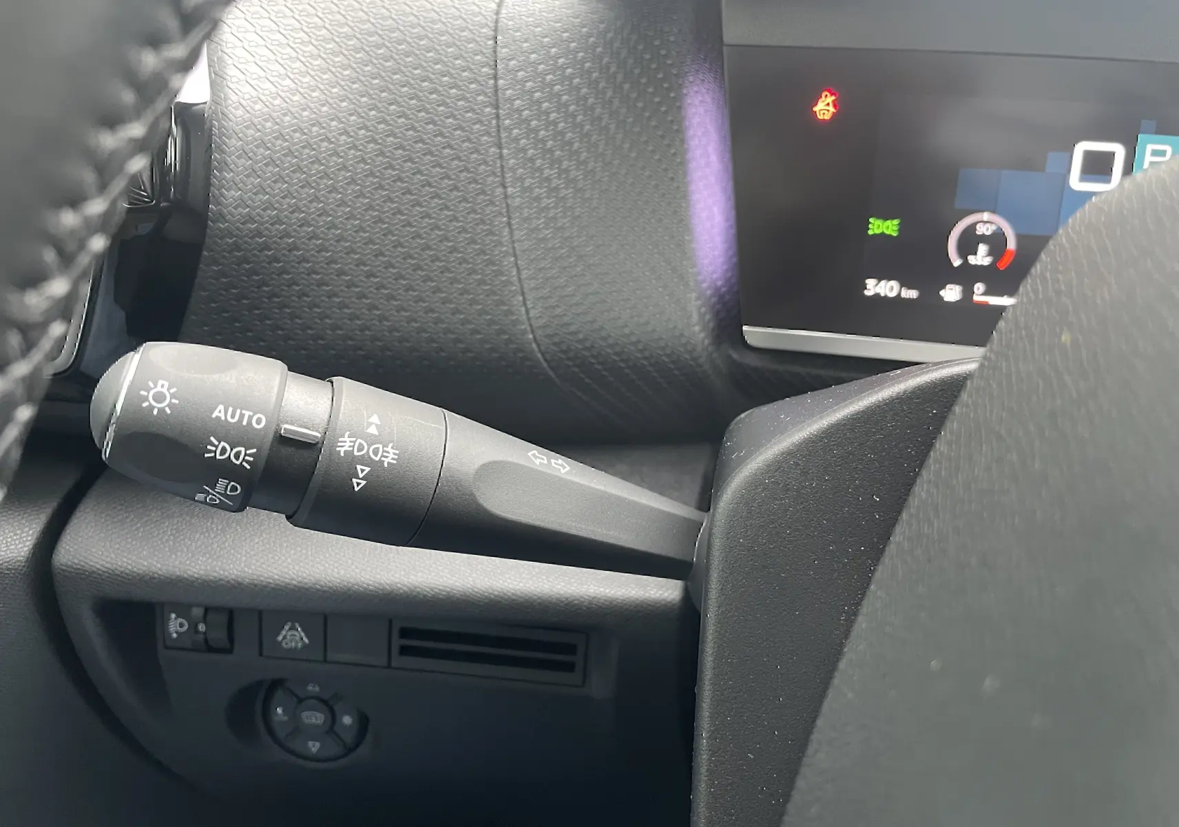 Gros plan sur la commande des phares et clignotants à gauche du volant dans l’habitacle gris-noir d’une Citroën C4 blanche 2022.