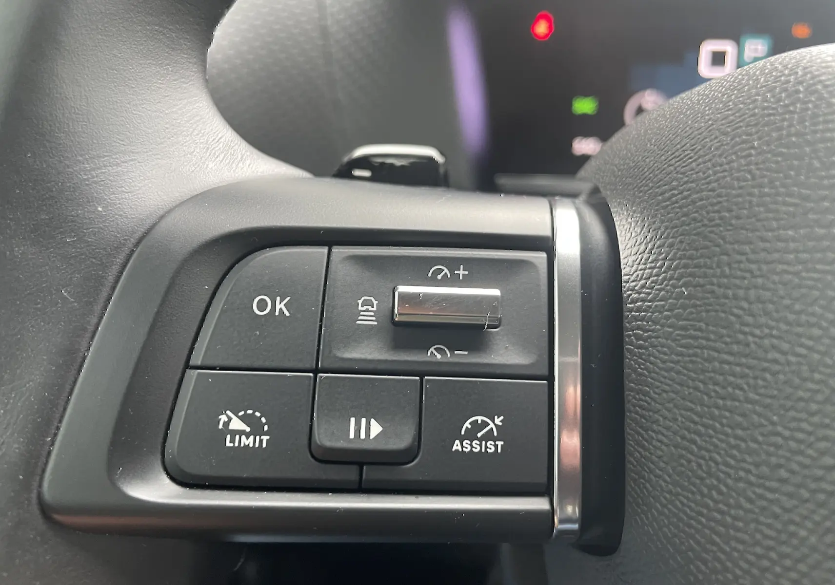 Gros plan sur les commandes au volant côté gauche de la Citroën C4 blanche, boutons de régulateur et assistant de conduite.
