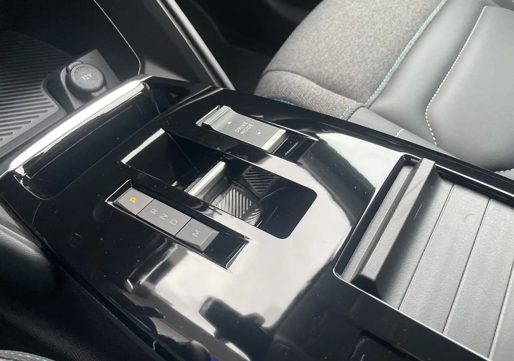 Gros plan sur la console centrale noire brillante de la Citroën C4 blanche, avec levier de vitesses automatique et siège tissu gris.