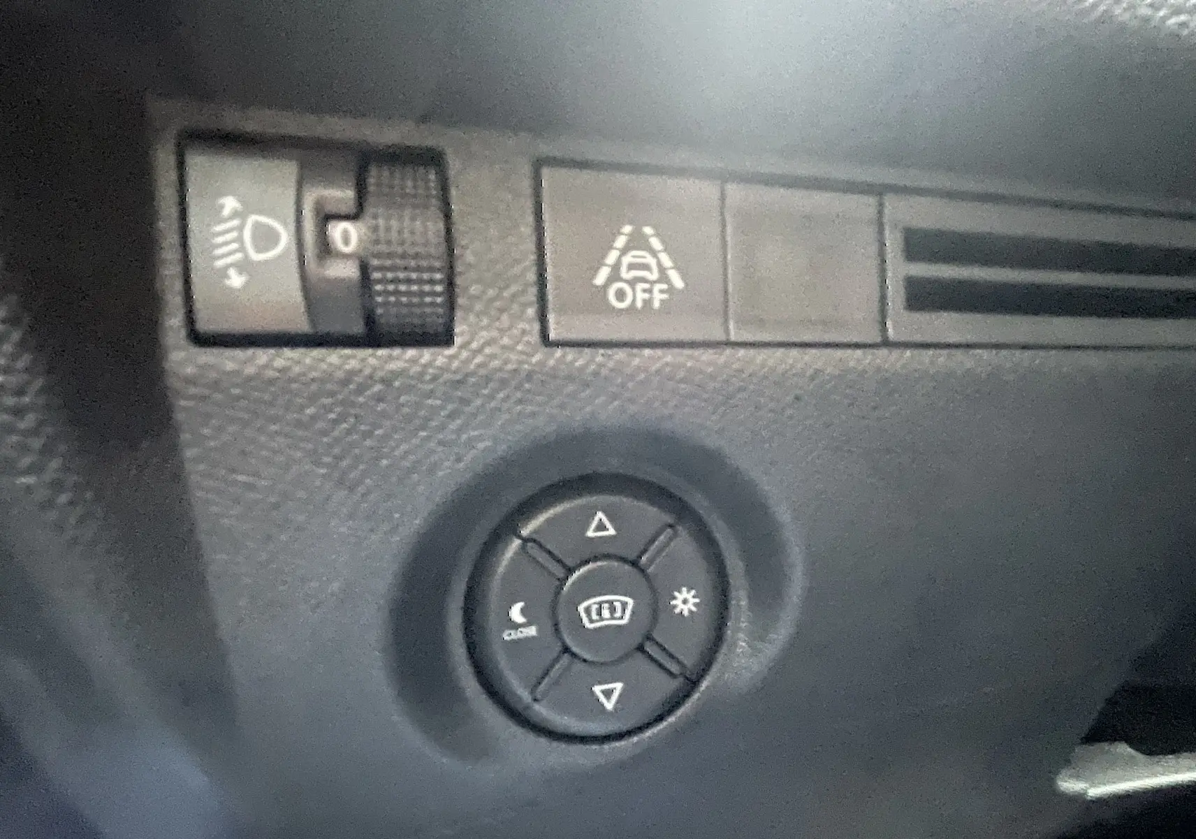 Détail des commandes d’éclairage et d’aide à la conduite sur le tableau de bord noir d’une Citroën C4 blanche.