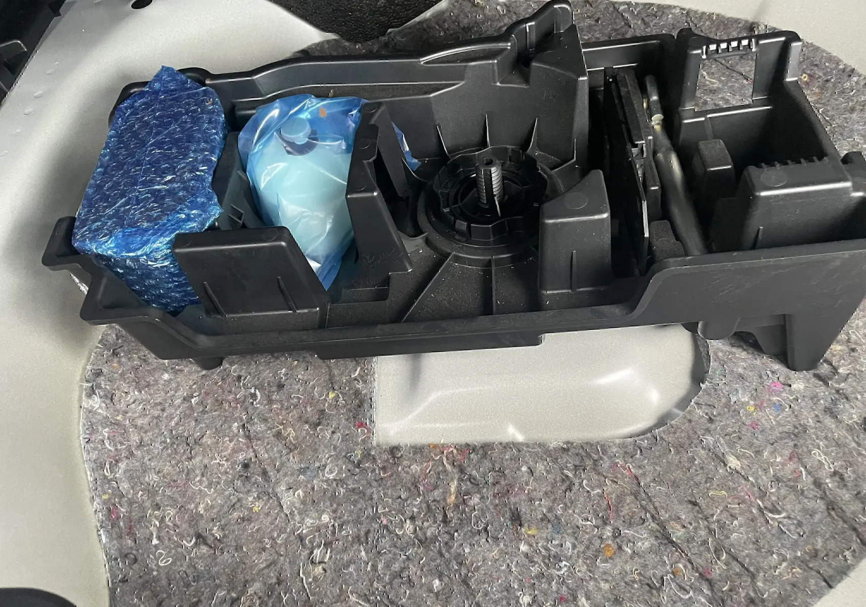 Vue rapprochée de l’espace de rangement sous le coffre blanc d’une Citroën C4 2022, avec outils et emballages.