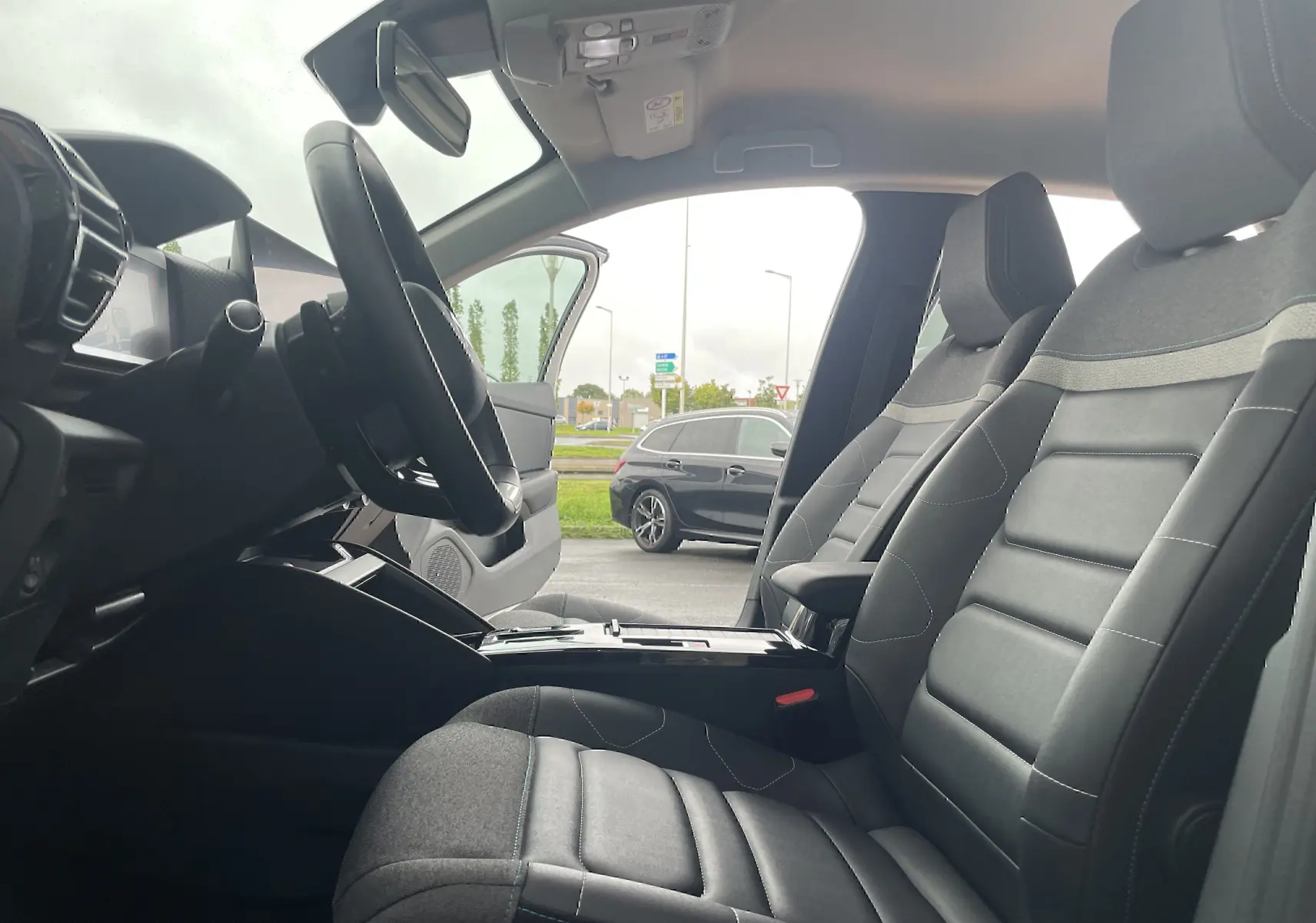 Vue intérieure côté gauche de la Citroën C4 2022, sièges tissu gris noir et volant multifonction visible.