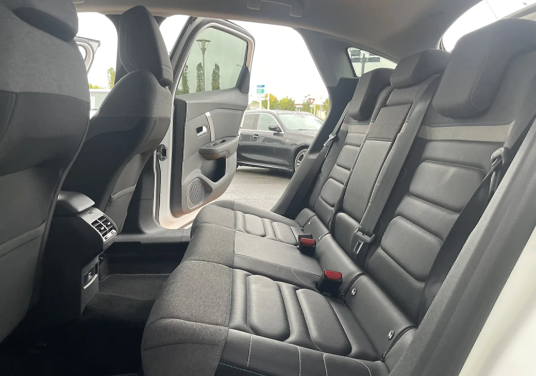 Vue intérieure arrière côté droit de la Citroën C4 blanche 2022, montrant les sièges arrière en tissu gris noir et la porte ouverte.