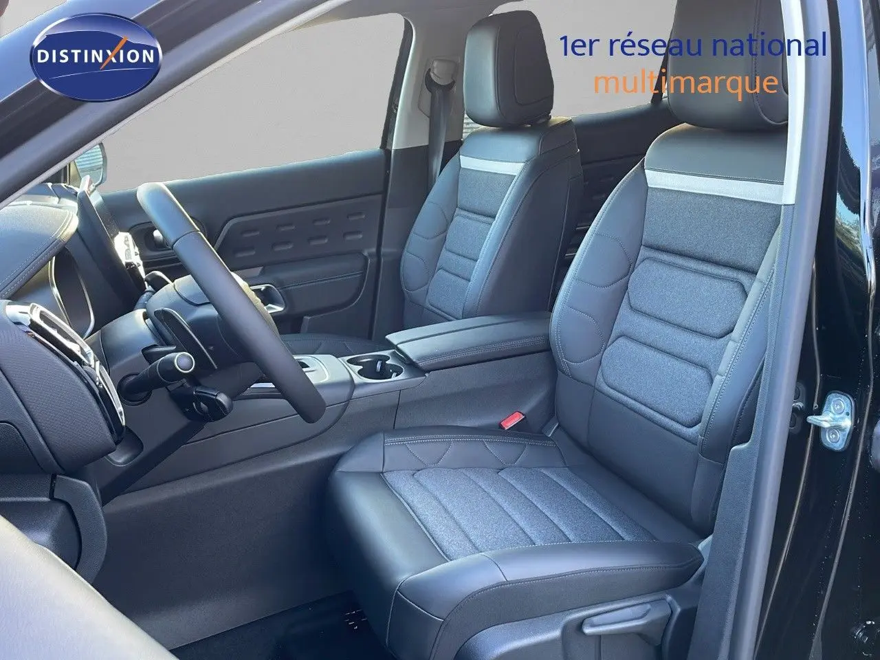 Intérieur côté conducteur de Citroën C5 Aircross noir Perla Metal avec sièges cuir et tissu gris, volant multifonction visible.