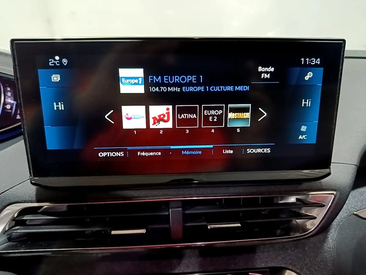 Écran tactile central affichant les stations radio, intérieur du Peugeot 3008 noir, vue rapprochée frontale.