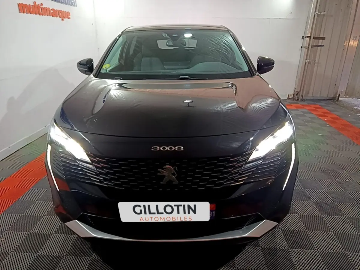 Vue avant d'un Peugeot 3008 noir 2022 avec phares LED allumés dans un garage intérieur.