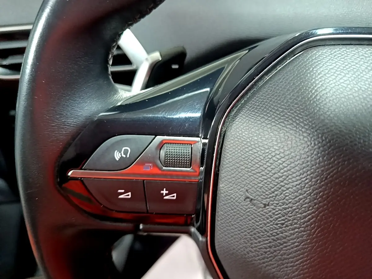 Gros plan sur le volant cuir noir côté gauche du Peugeot 3008 2022 avec commandes multifonctions intégrées.