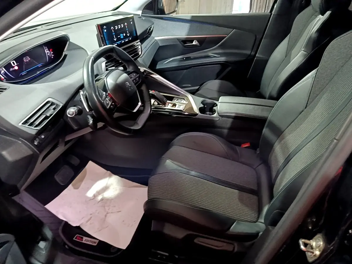 Vue intérieure côté conducteur du Peugeot 3008 noir, volant cuir multifonctions et écran tactile central visible.