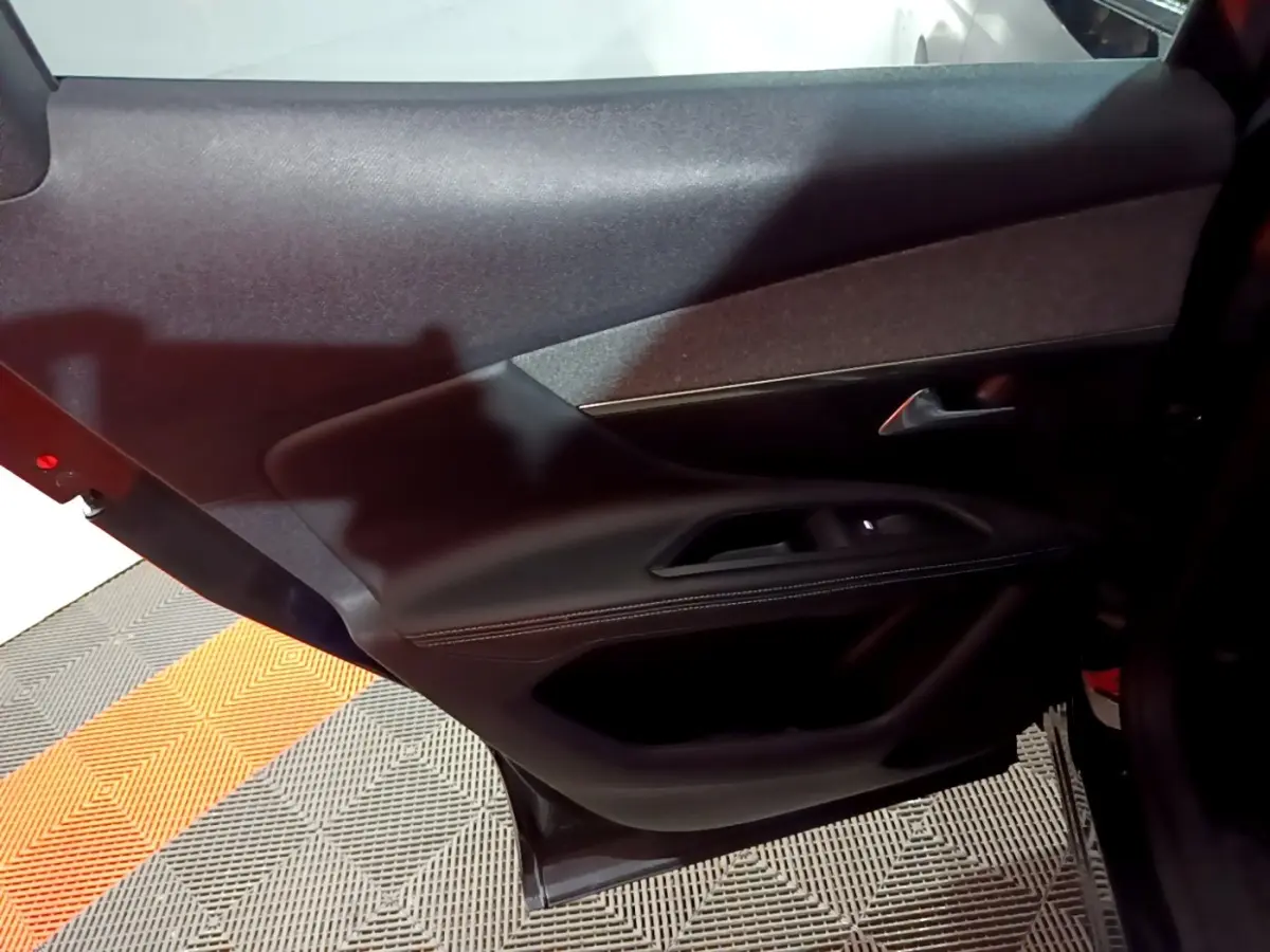 Vue rapprochée de la porte arrière gauche noire du Peugeot 3008 2022, avec garniture en cuir et commandes de fenêtre.