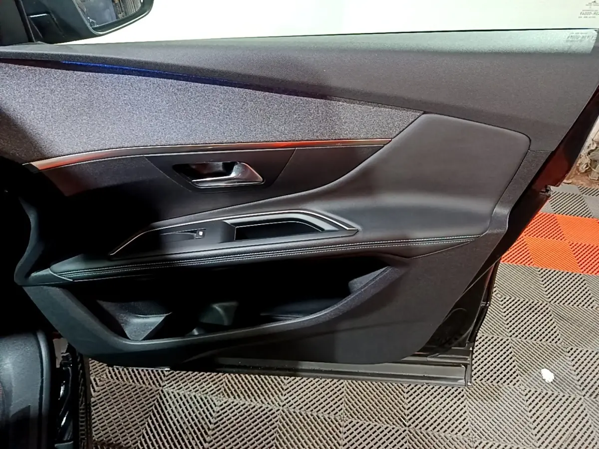 Gros plan sur la porte intérieure côté conducteur noire du Peugeot 3008 2022 avec poignée métallique et surpiqûres blanches.