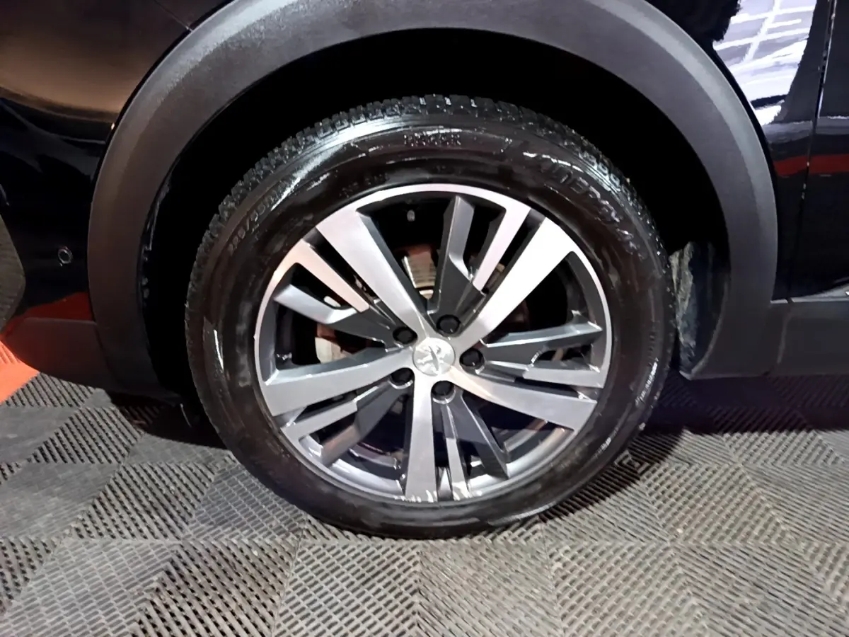 Gros plan sur la roue arrière droite du Peugeot 3008 noir, mettant en valeur la jante alliage moderne.