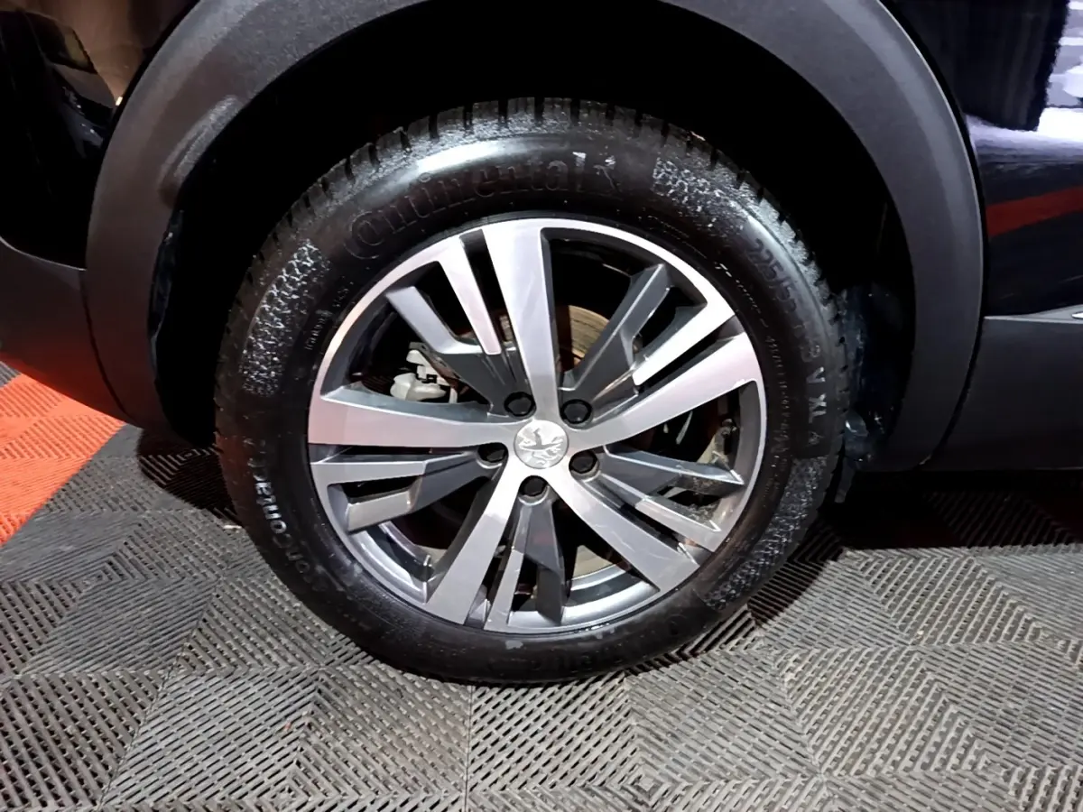 Gros plan sur la roue avant droite du Peugeot 3008 noir, avec jante alliage et pneu Continental visible.