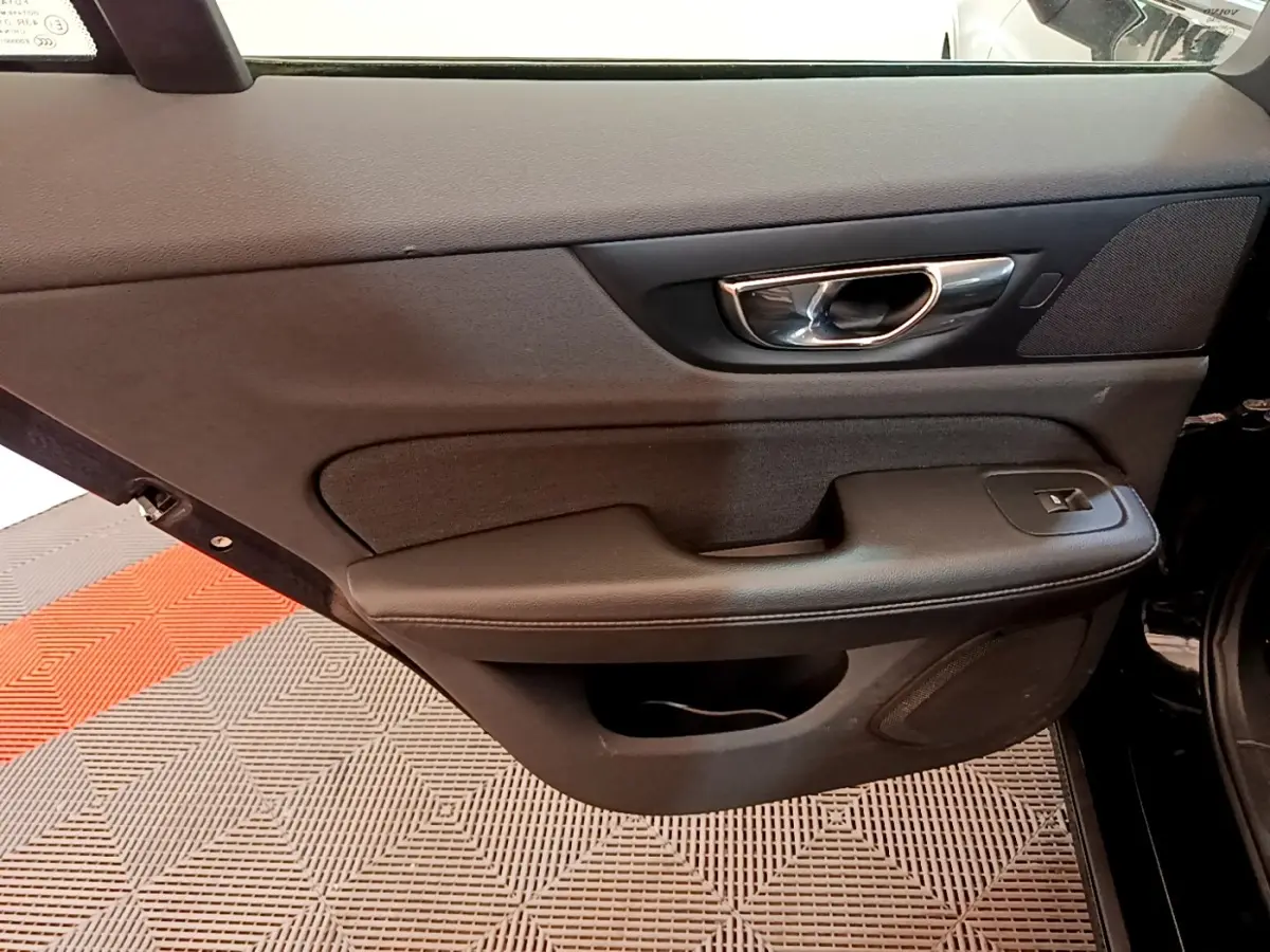 Vue intérieure du panneau de porte avant droit noir du Volvo V60 D3 AdBlue 2020 avec poignée chromée et commande de vitre électrique.