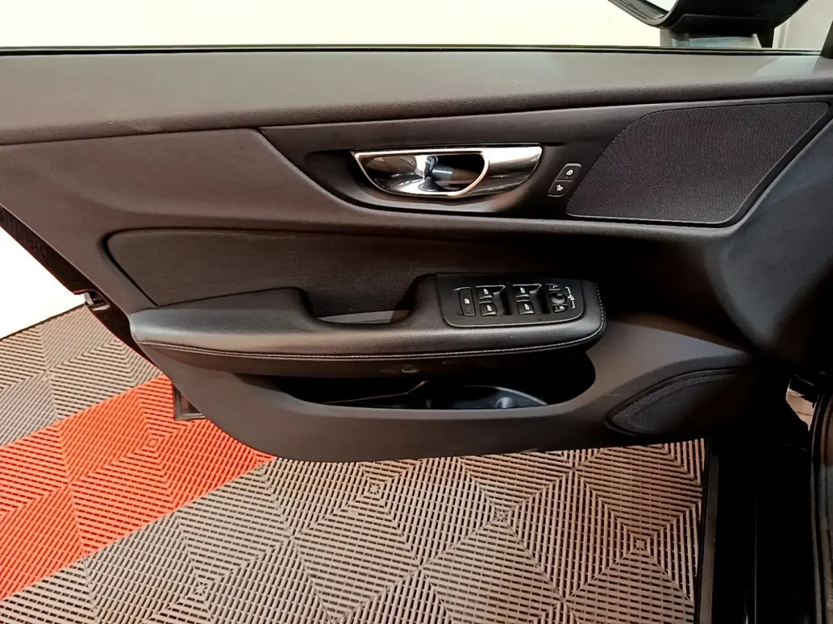 Vue intérieure sur la porte avant gauche noire d'une Volvo V60 2020 avec commandes électriques et poignée chrome.