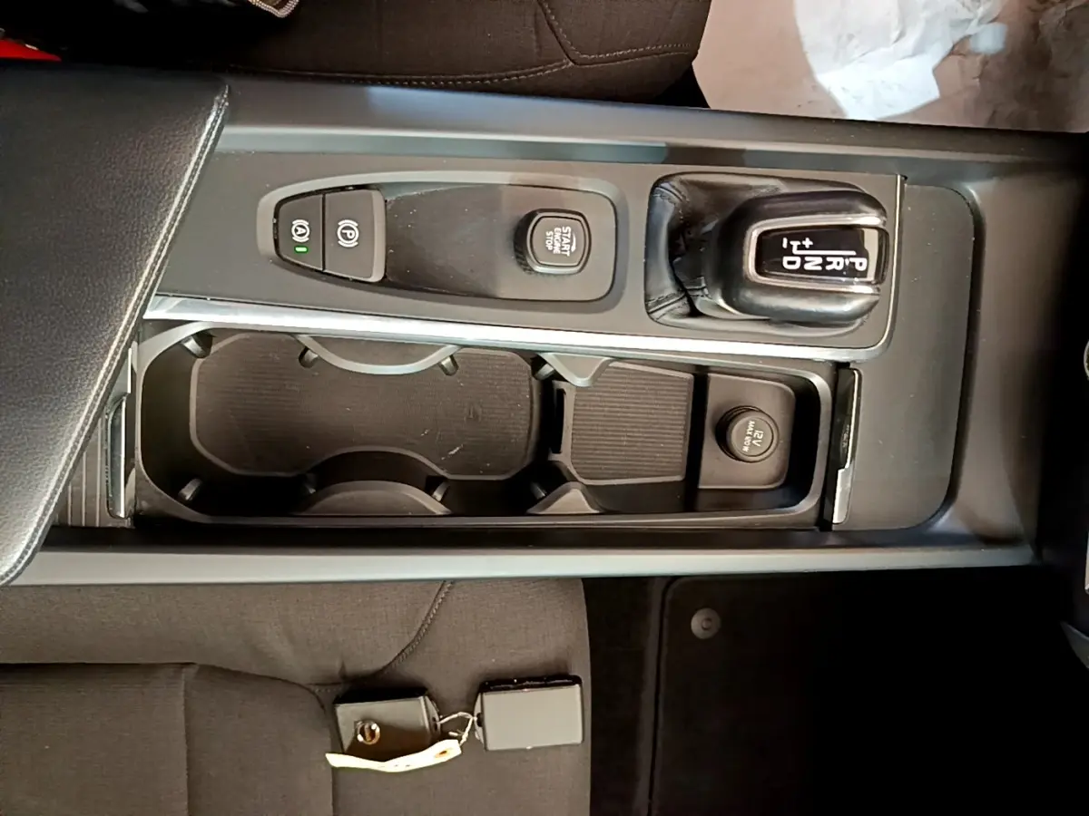 Vue plongeante sur la console centrale noire du Volvo V60 2020, montrant levier de vitesse automatique et bouton start/stop.