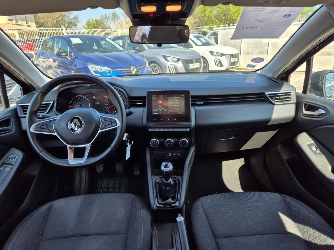 Vue intérieure avant de la Renault Clio V TCe 90 Equilibre 2022, tableau de bord noir avec écran tactile et boîte manuelle.