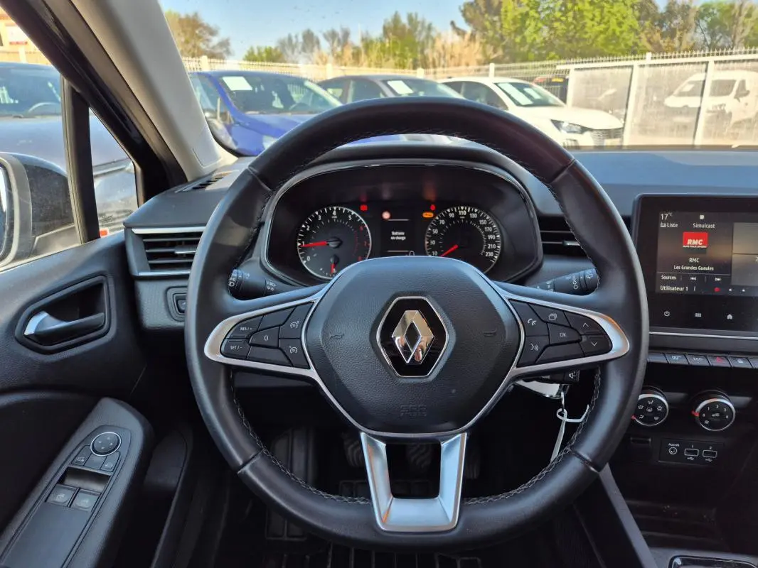 Vue intérieure centrée sur le volant noir de la Renault Clio 2022, avec tableau de bord et écran multimédia visibles.