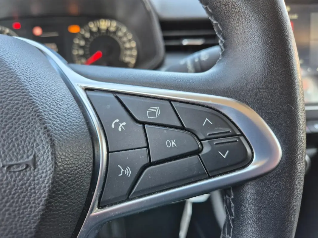 Gros plan sur les commandes multifonctions à droite du volant d’une Renault Clio noire, version V TCe 90 Equilibre.
