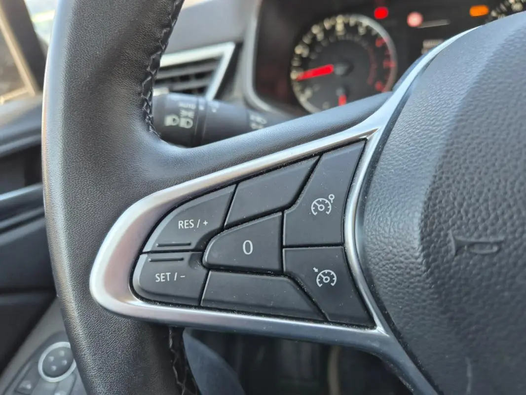 Gros plan sur les commandes du régulateur de vitesse au volant noir de la Renault Clio V TCe 90 Equilibre 2022.