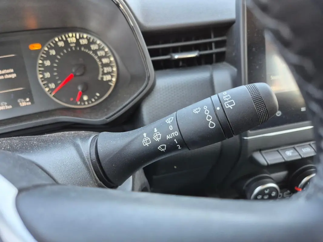Gros plan sur la commande de détecteur de pluie à droite du volant d’une Renault Clio noire, tableau de bord en arrière-plan.