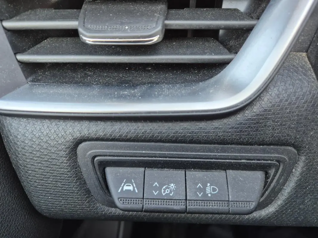 Gros plan sur les commandes de réglage d'assistance à la conduite et éclairage dans une Renault Clio noire 2022.
