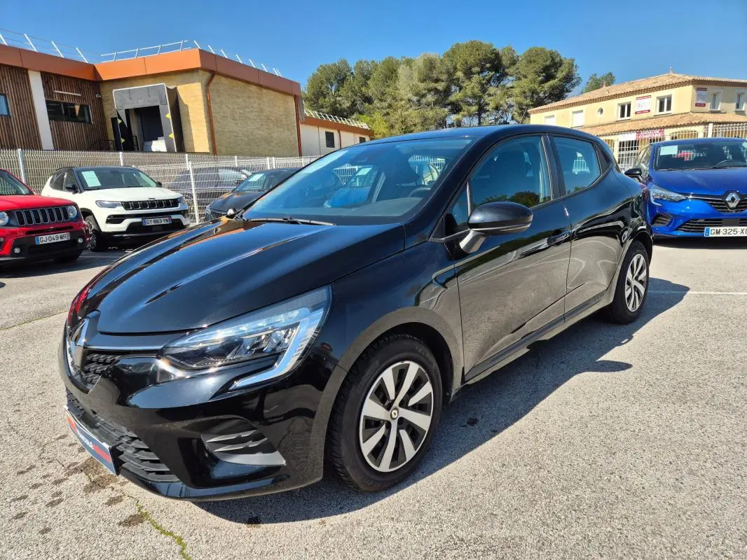Renault Clio V TCe 90 Equilibre noire vue 3/4 avant droit sur parking ensoleillé avec jantes spécifiques.