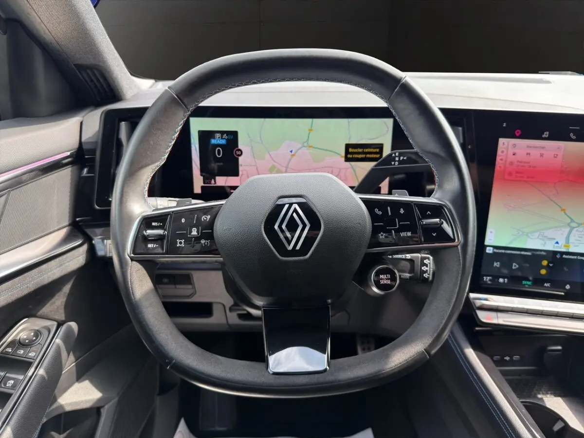 Vue intérieure centrée sur le volant cuir et suède avec logo Renault, écran tactile et tableau de bord numérique du Renault Espace 2024.