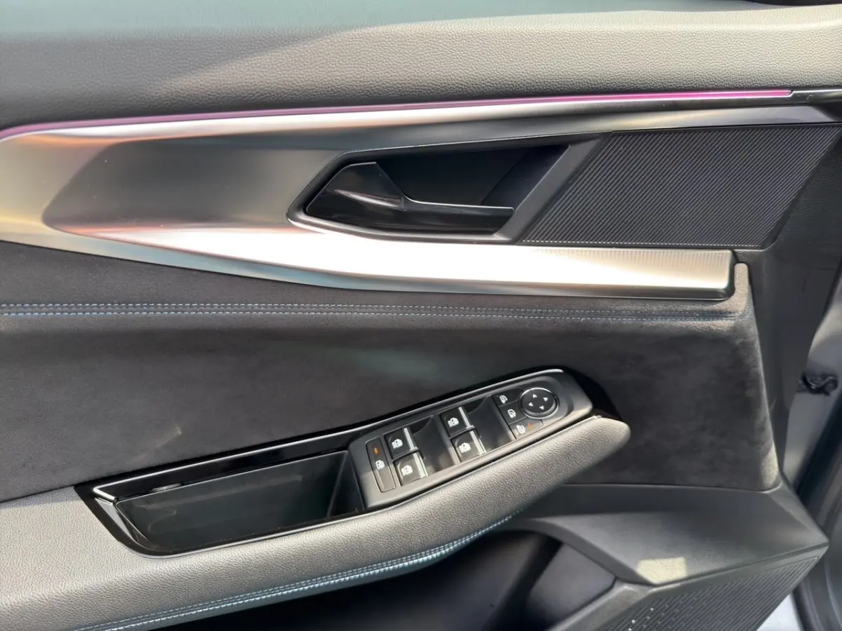 Détail de la porte côté conducteur du Renault Espace gris foncé, avec commandes électriques des vitres et éclairage d'ambiance violet.